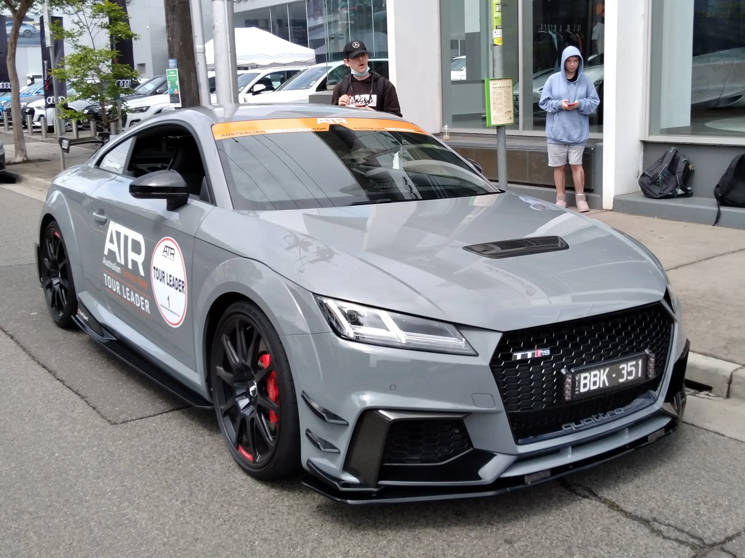 Silver Audi TT RS coupe parked on a sunny road.