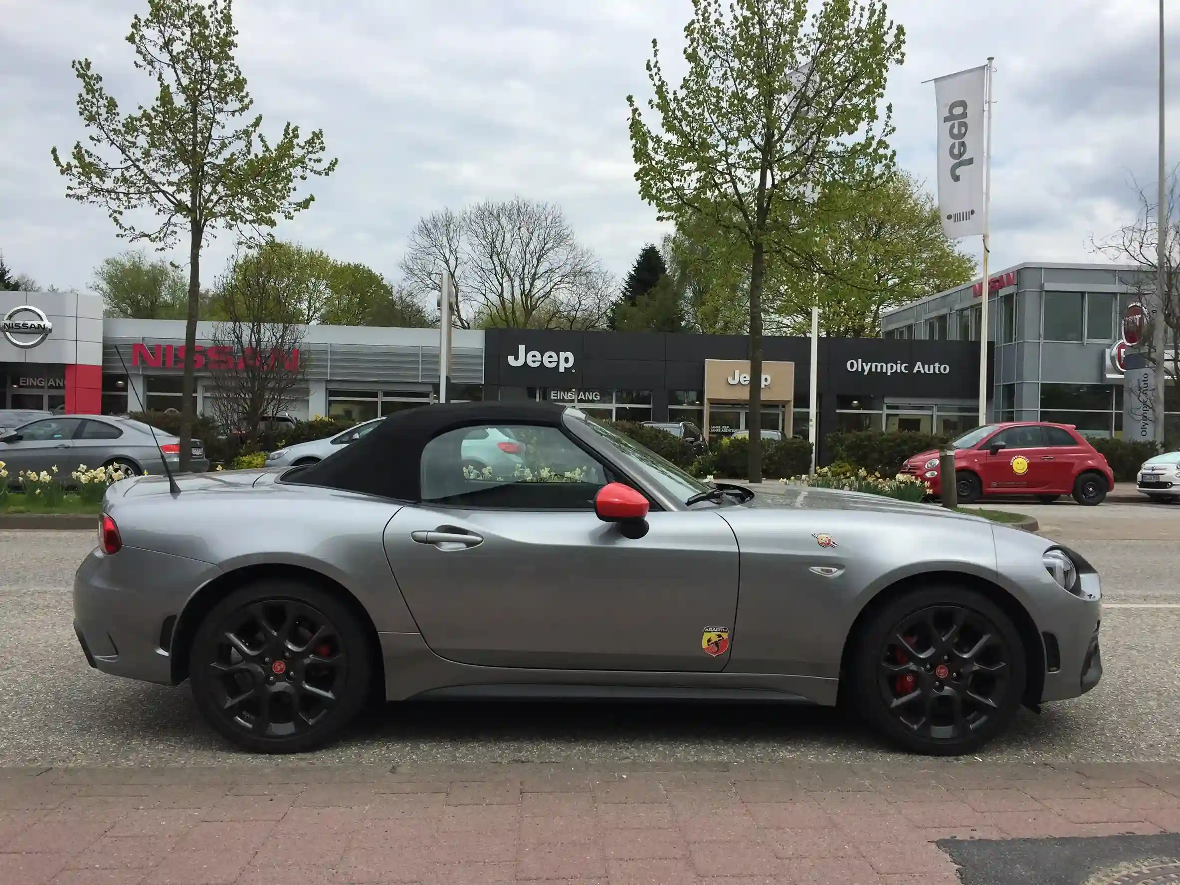 Red Fiat 124 Spider Abarth parked on a sunny road
