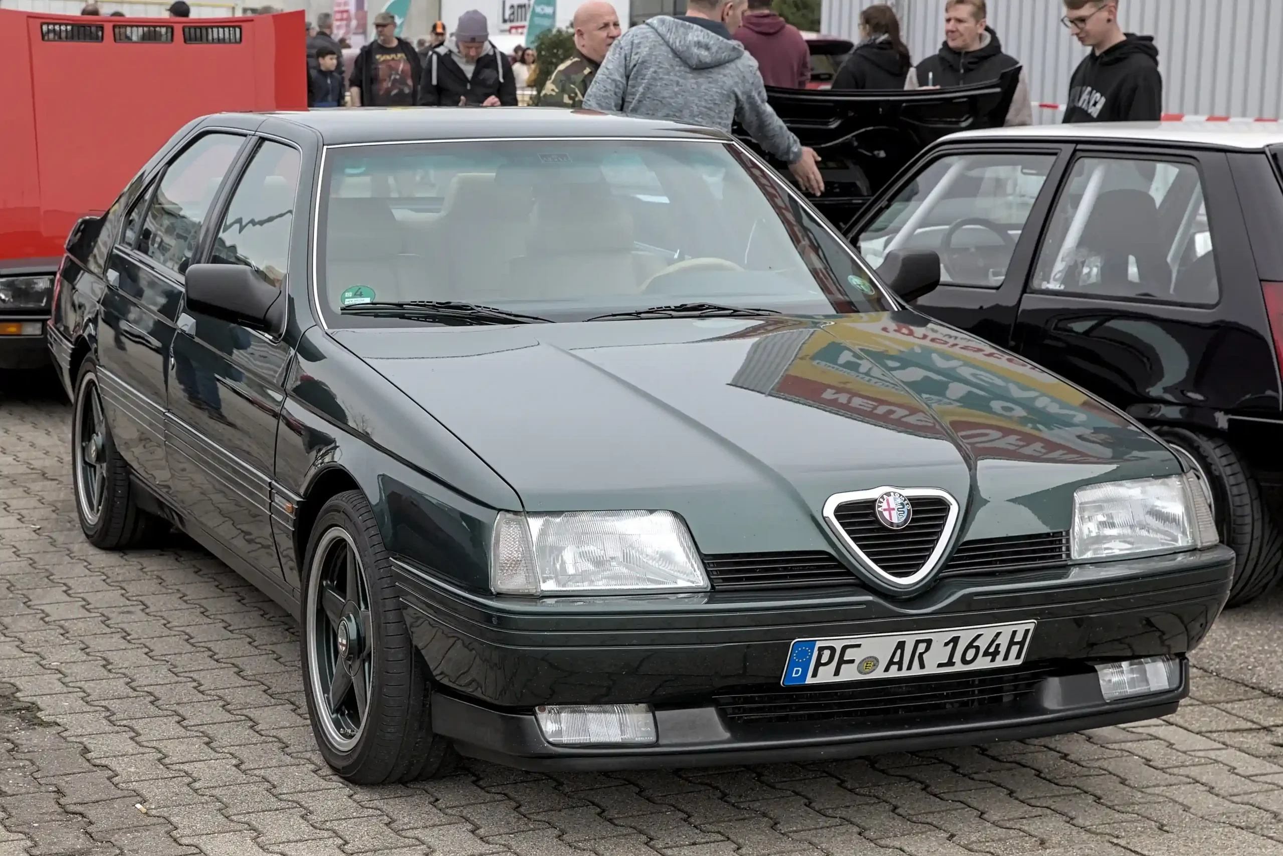 Sleek red Alfa Romeo 164, a classic Italian sedan.