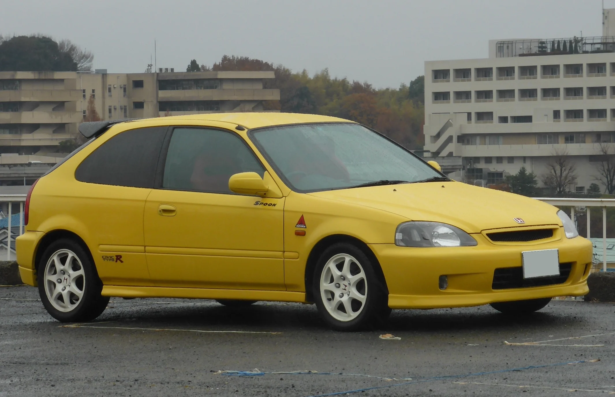 A vibrant yellow Honda Civic Type R EK9 on the road.