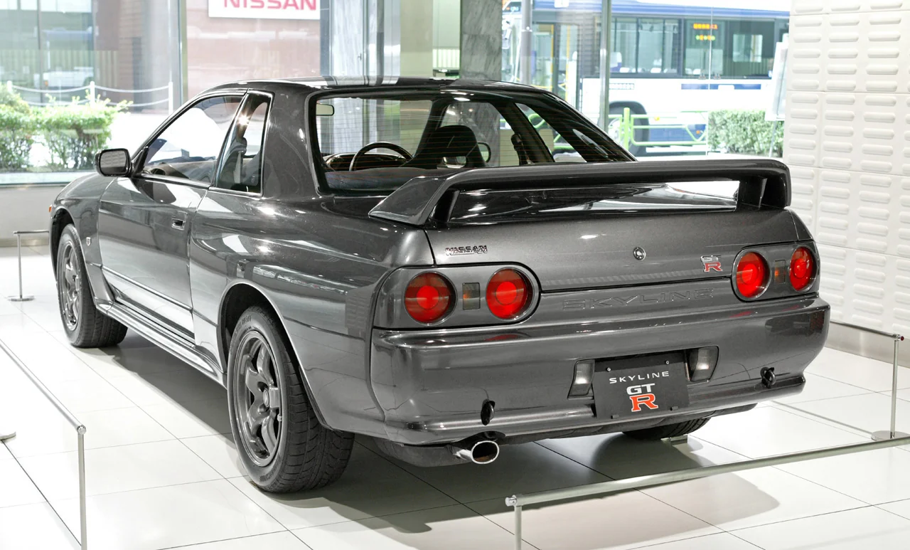 Silver Nissan Skyline R32 GT-R parked; iconic Japanese sports car.