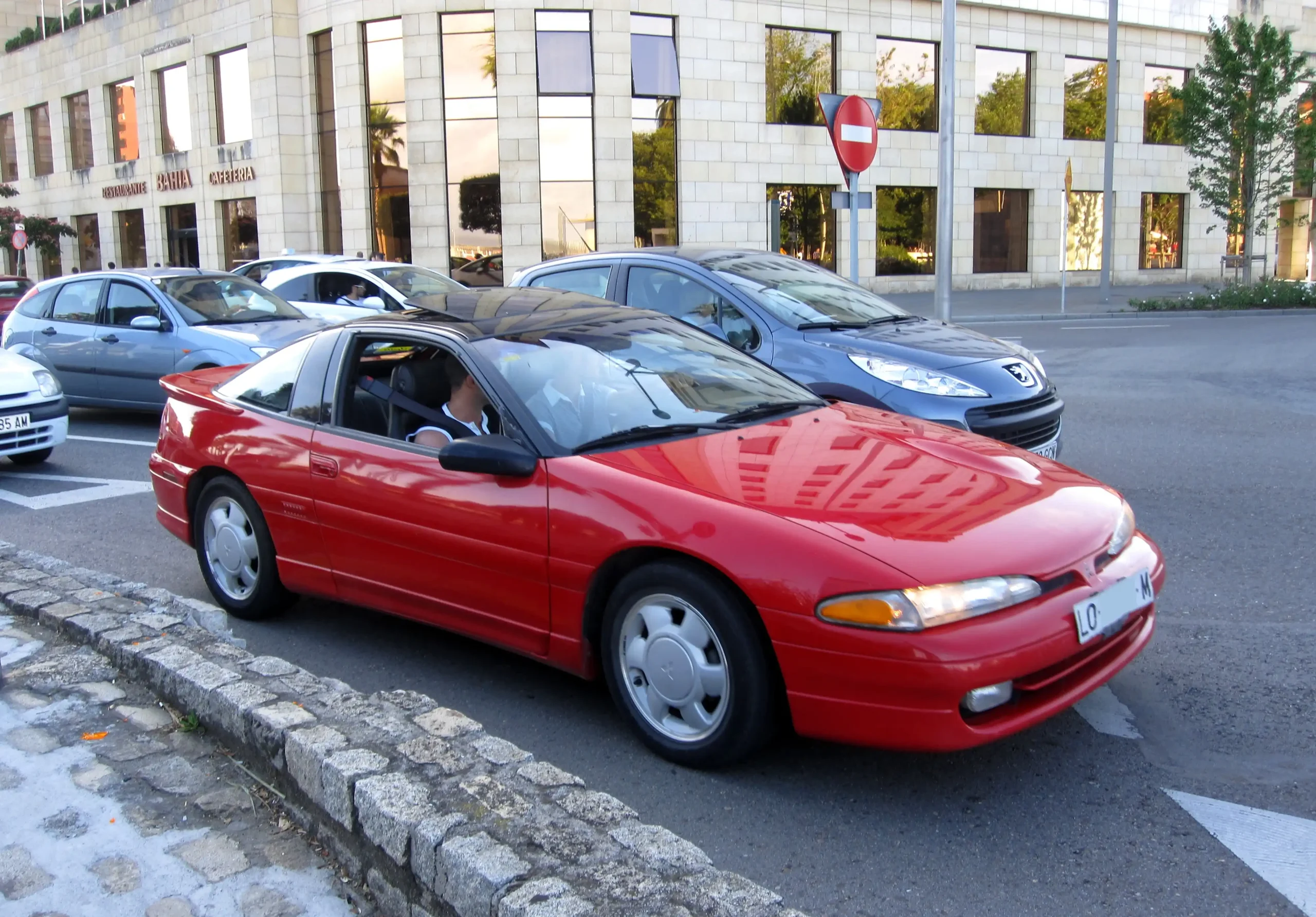 Red Mitsubishi Eclipse GSX parked on a sunny street, a sporty coupe.