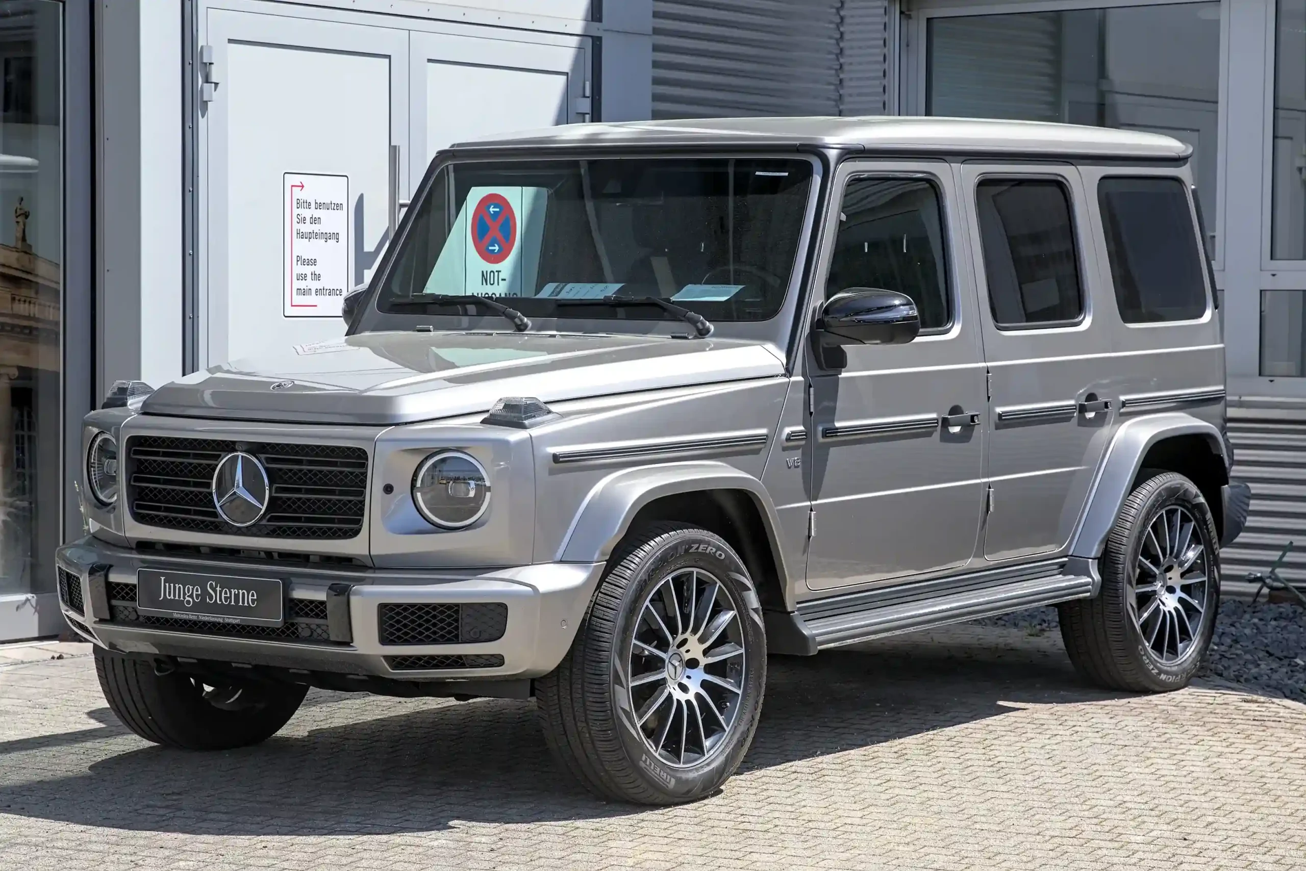 Silver Mercedes-Benz G 500 SUV driving on a paved road.