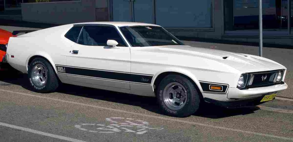 White 1973 Ford Mustang Mach 1 classic muscle car with black stripes parked on street