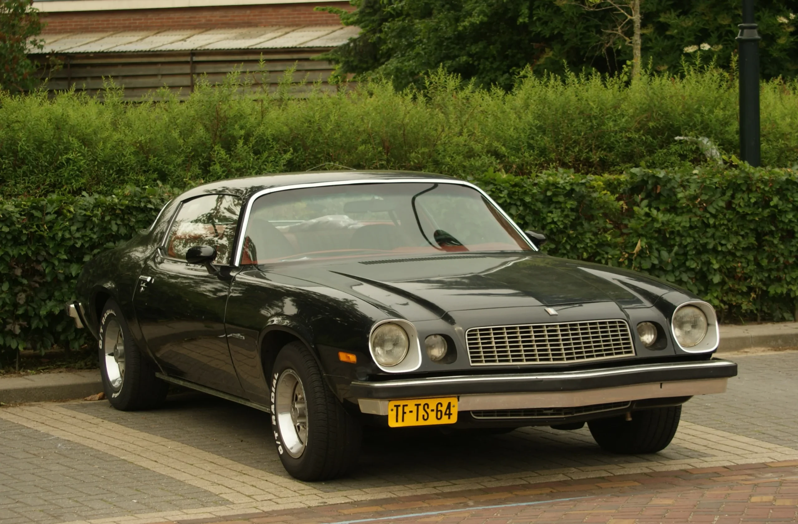 Classic 1975 Chevrolet Camaro, vibrant red paint, parked in sunlight