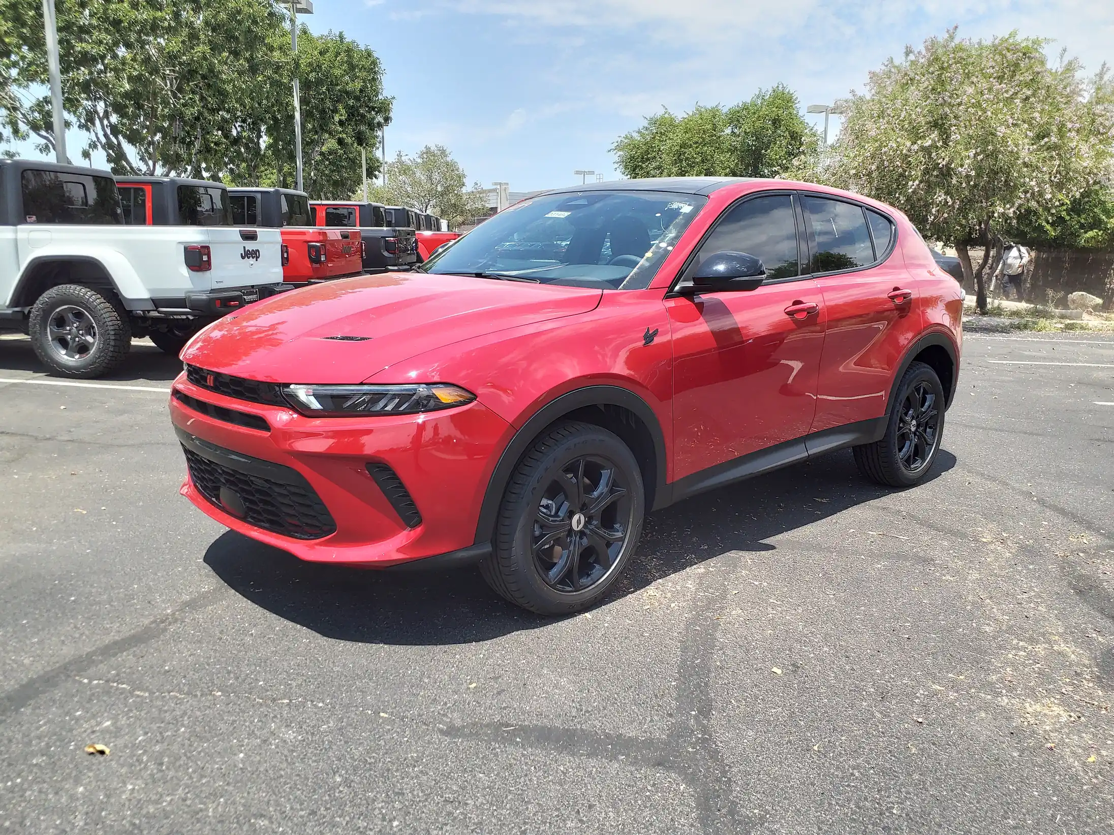Red Dodge Hornet GT Plus parked on a city street, sporty SUV.