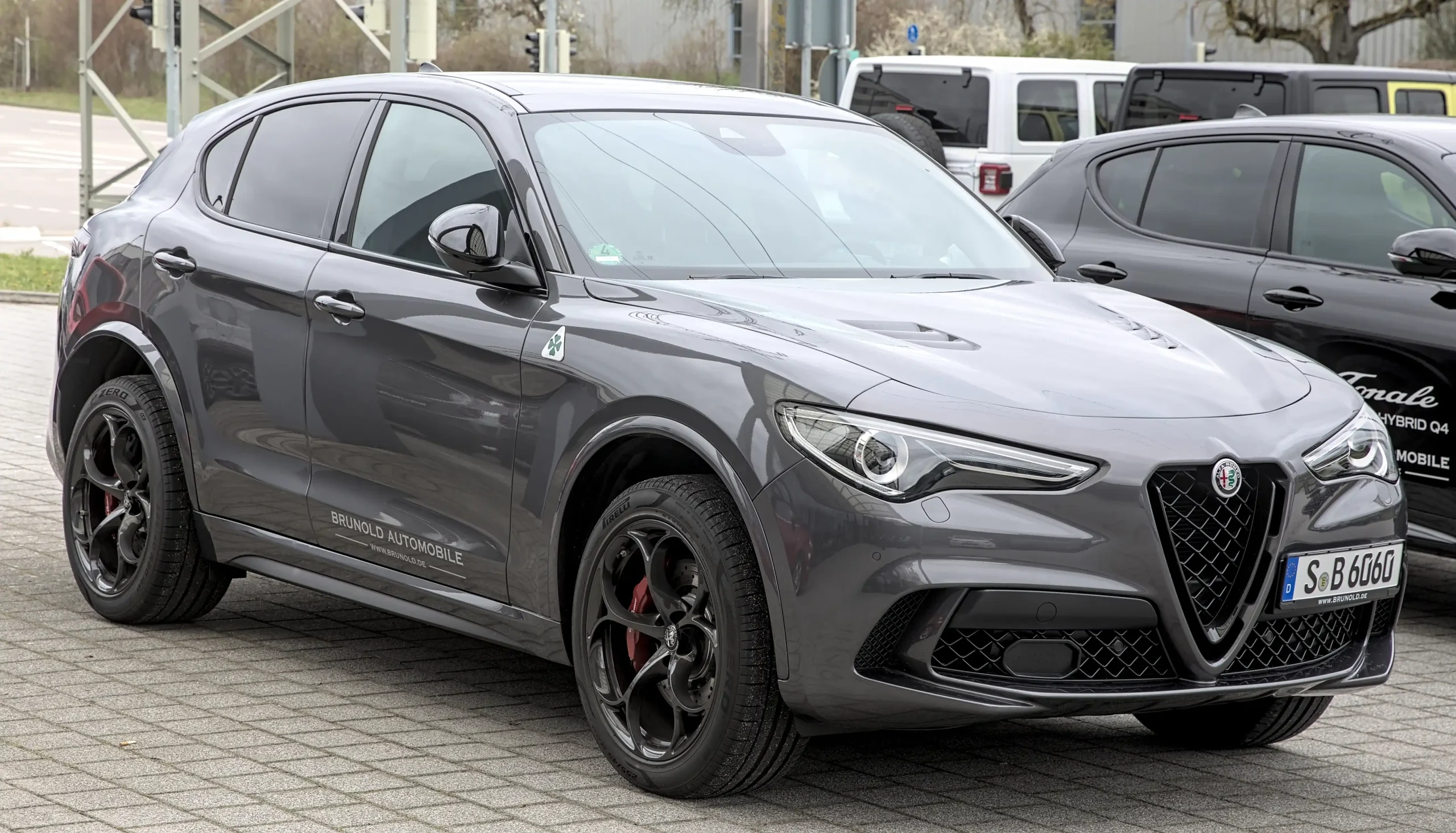 Red Alfa Romeo Stelvio SUV parked on a scenic road.
