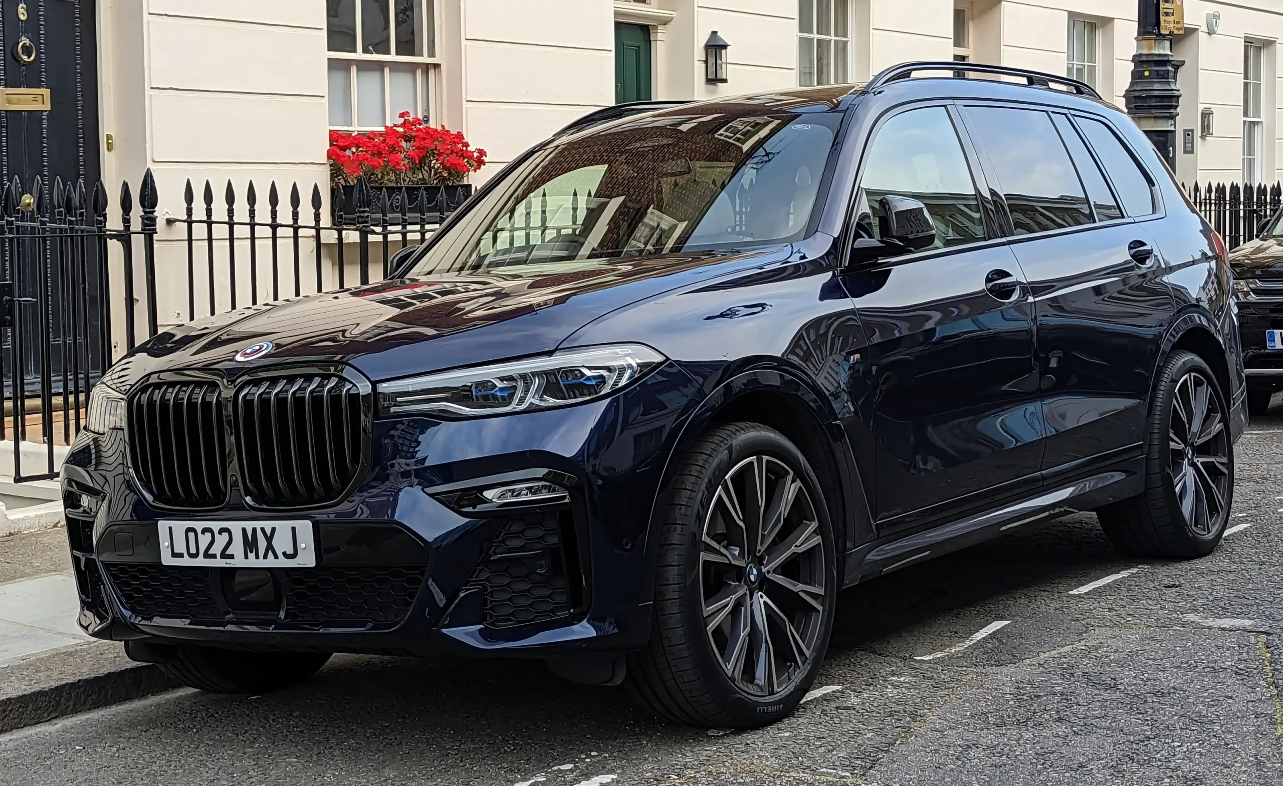 Silver BMW X7 M50i parked, showcasing its large grille and sleek design.
