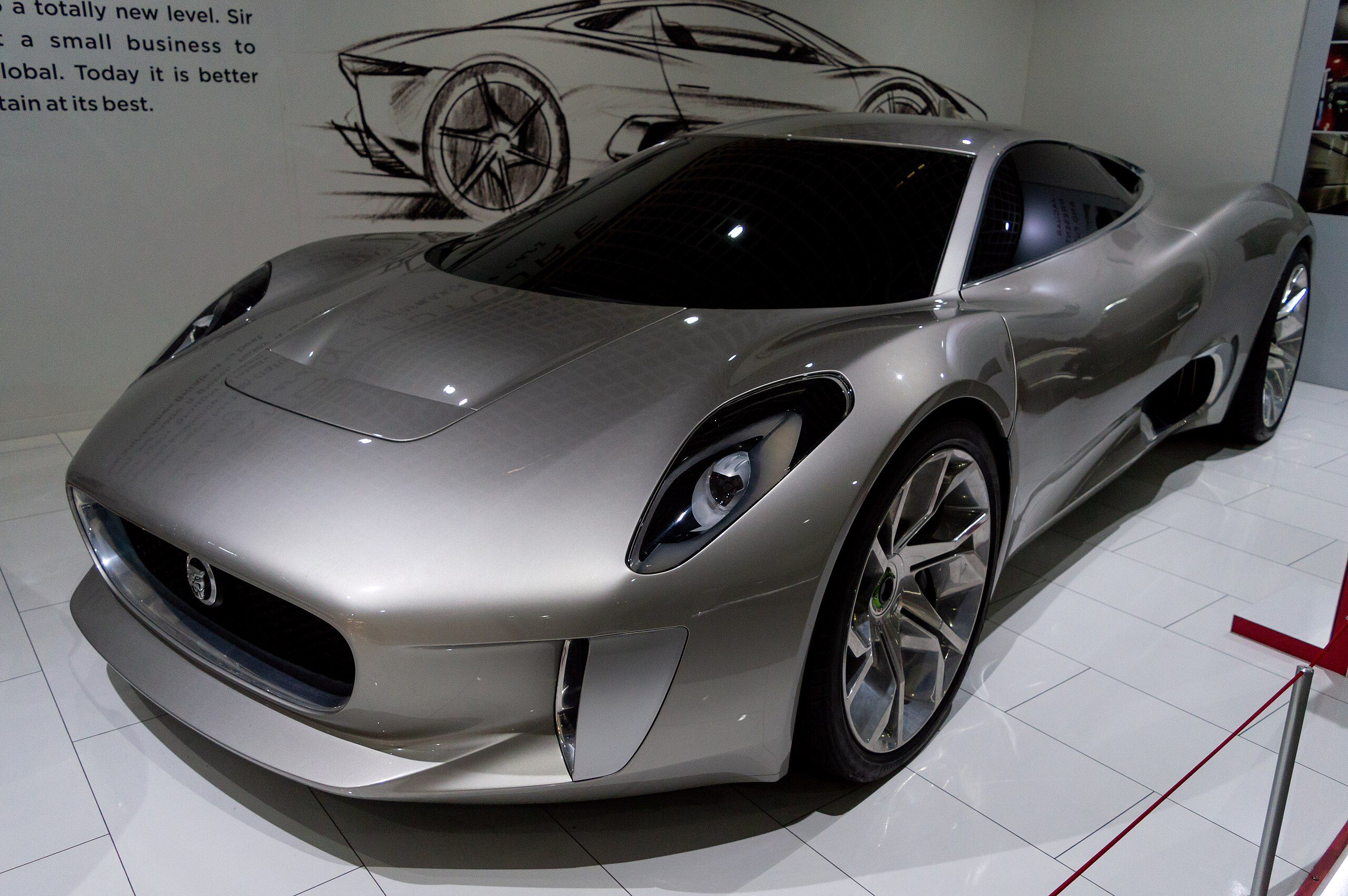 Sleek silver Jaguar CX75 sports car with scissor doors, displayed at showroom