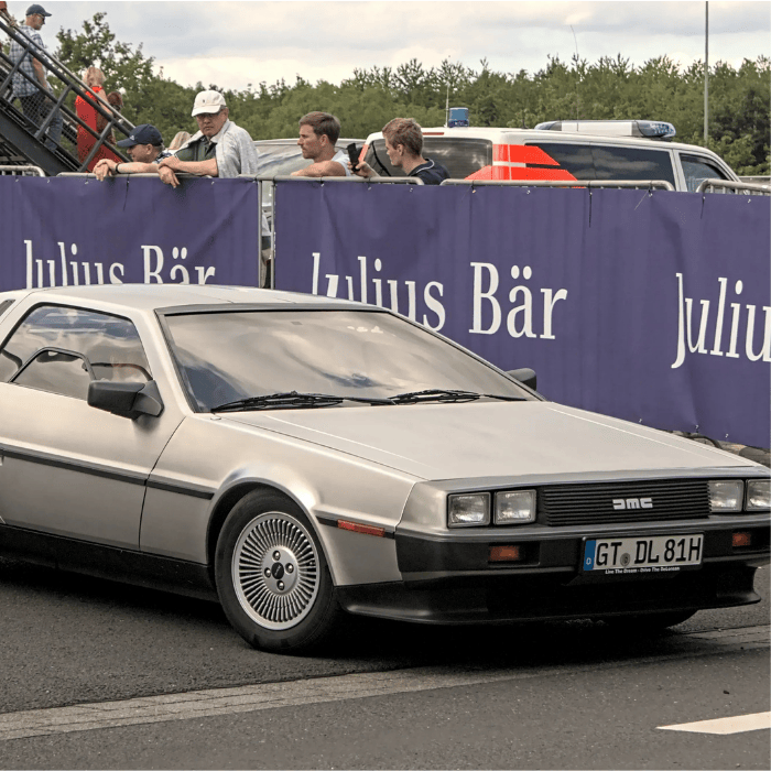 Silver DeLorean DMC-12 parked, iconic gull-wing doors slightly open.