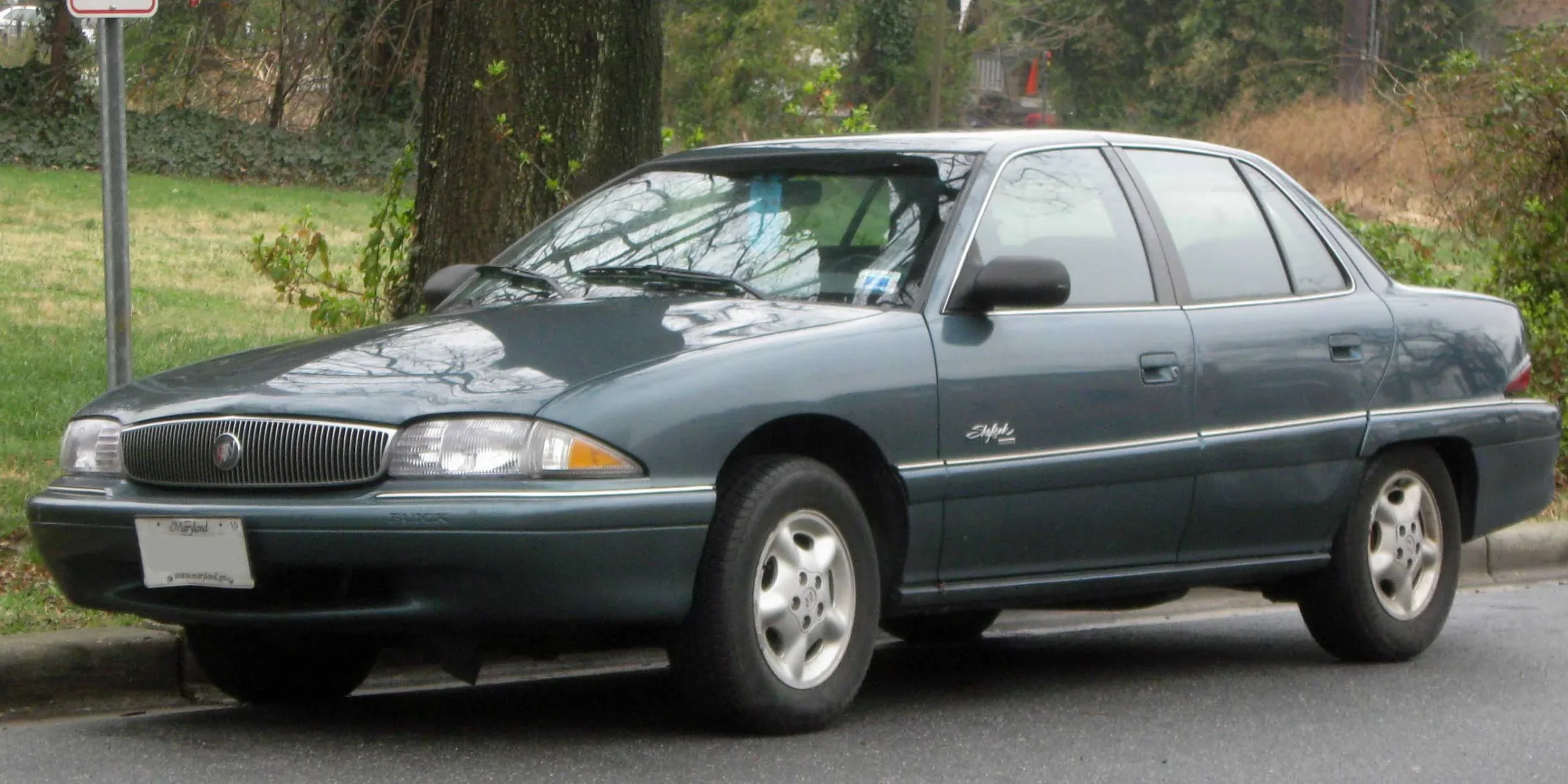 Mid-1990s Buick Skylark sedan, silver, parked on pavement, daytime.