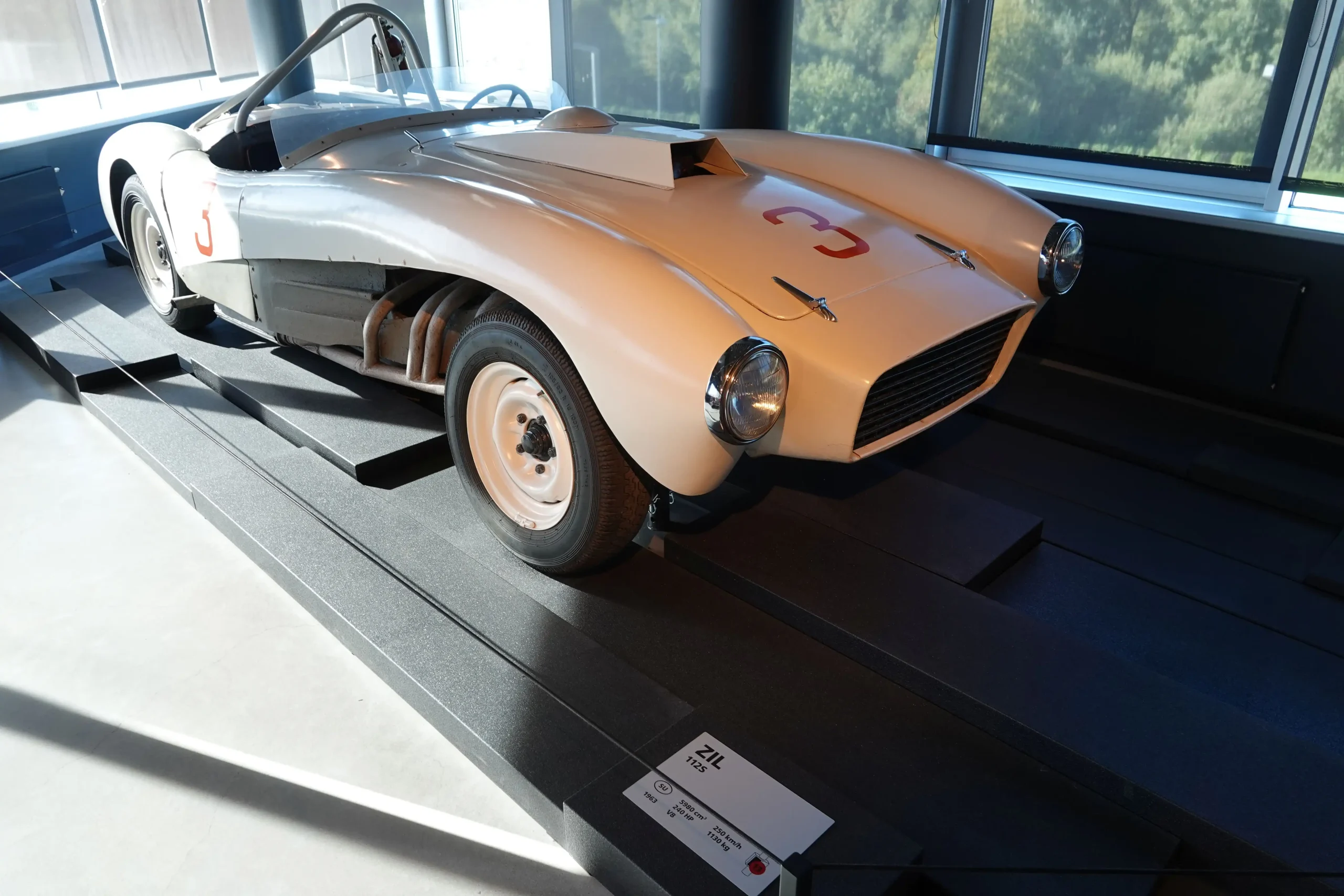 Sleek, red ZIL-112 sports car with long hood and fins.