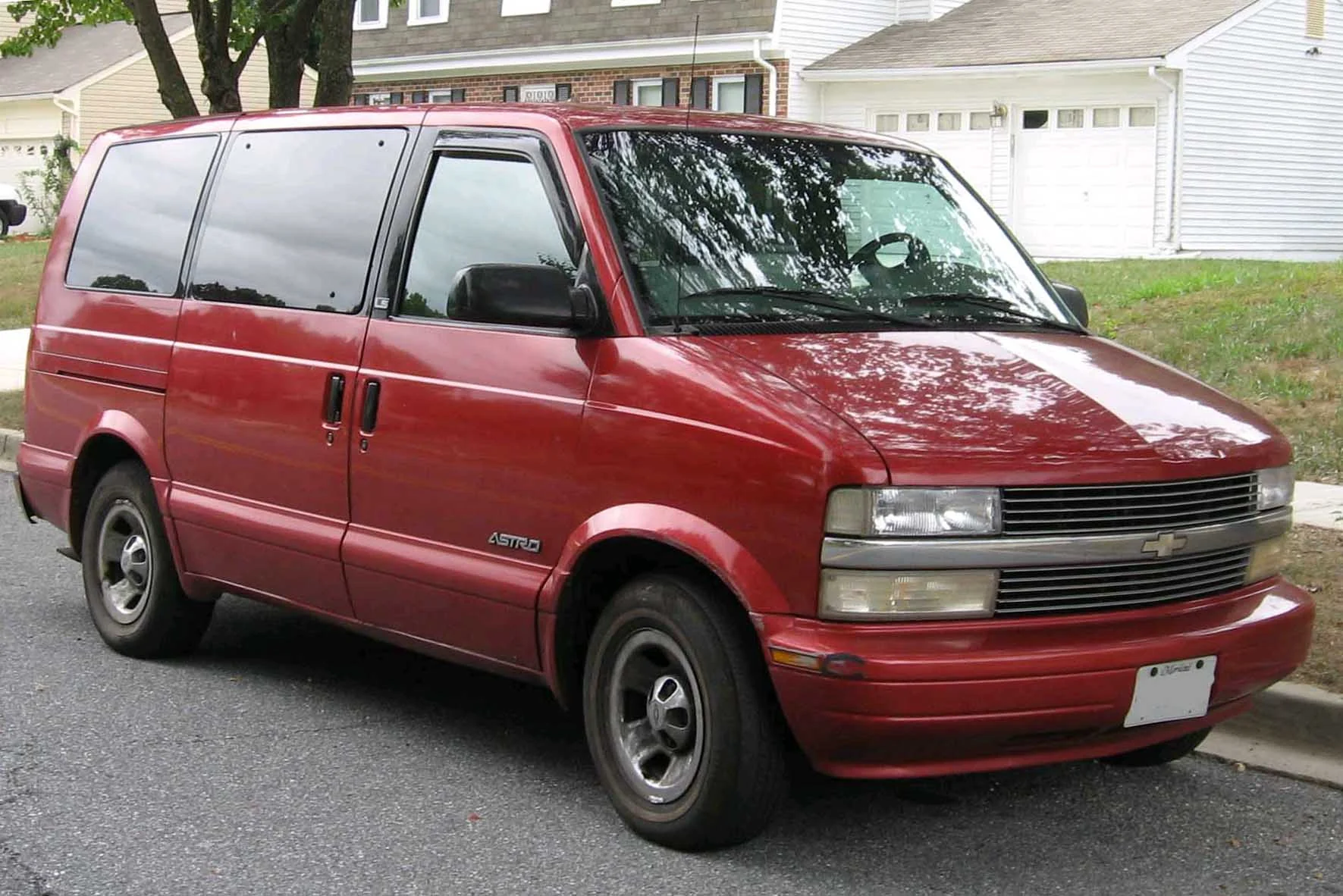 Silver Chevrolet Astro van parked on a sunny suburban street.