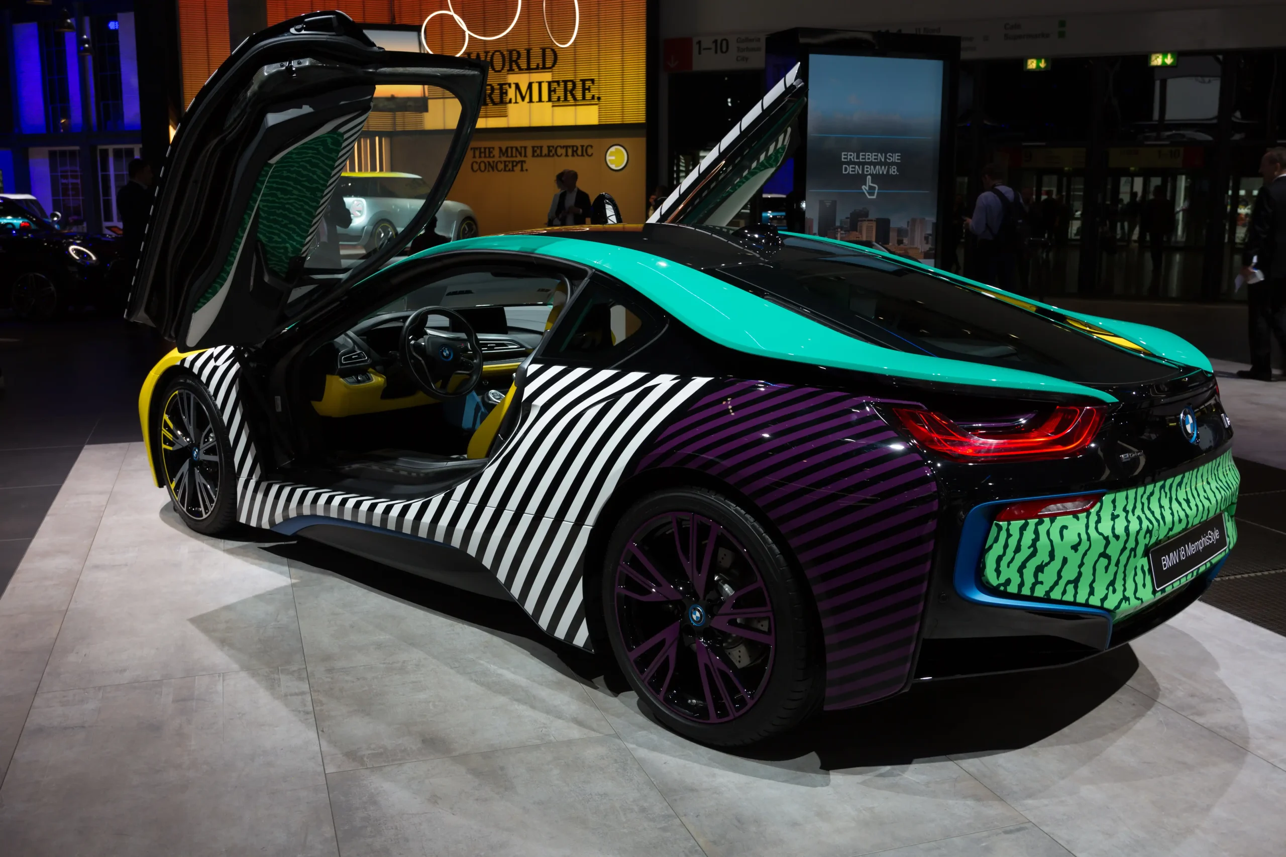 Sleek silver BMW i8, futuristic hybrid sports car, parked on street.