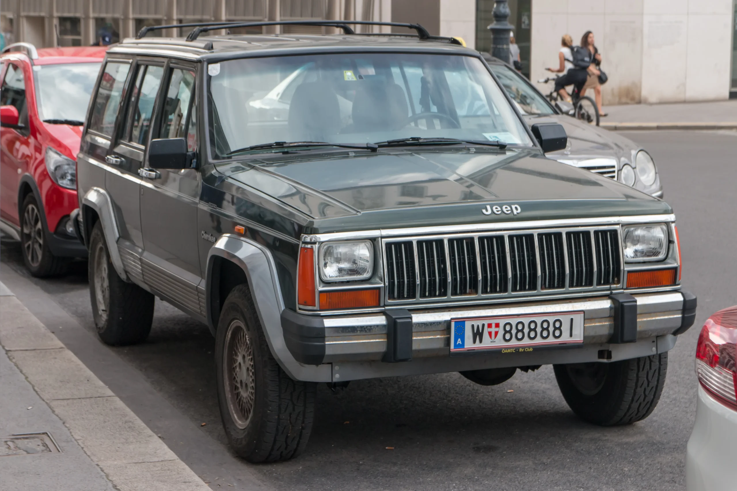 Red Jeep Cherokee XJ parked on a sunny, gravel road.