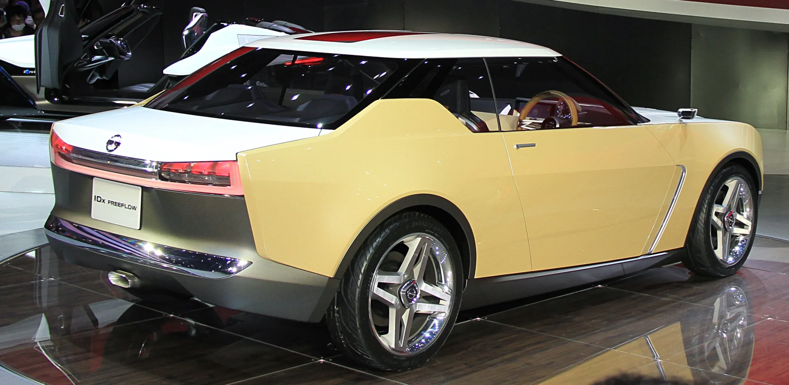 Sleek, retro-inspired Nissan IDx concept car in a vibrant setting.