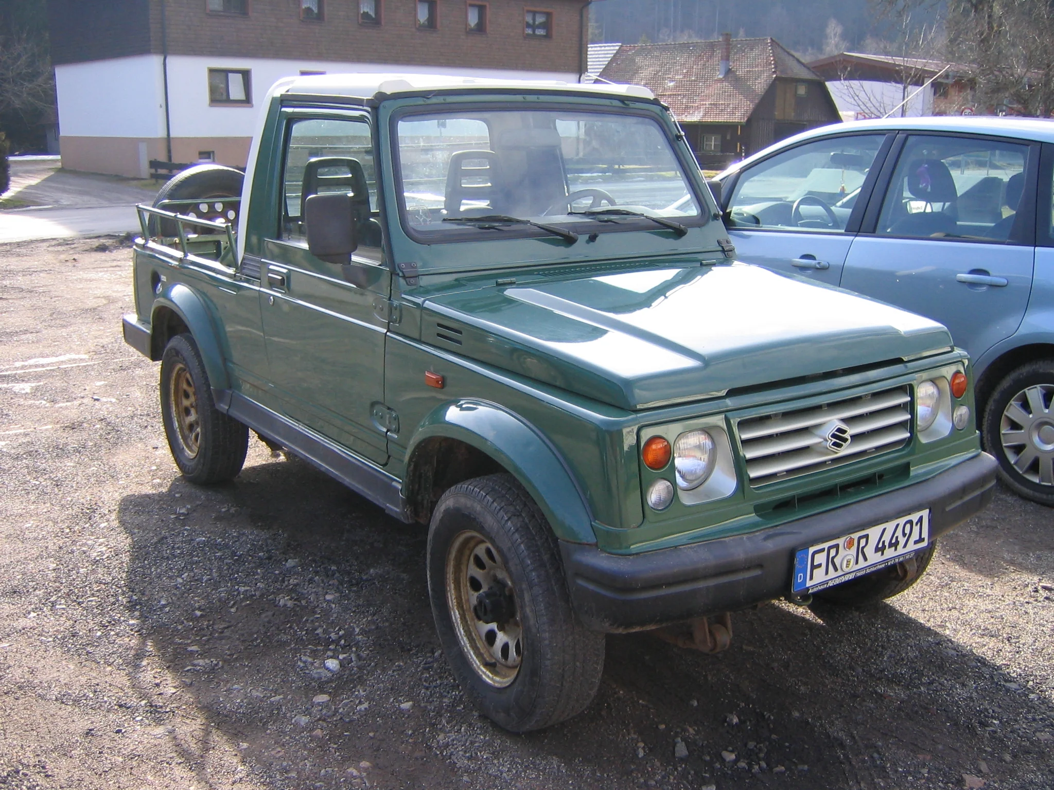 Red Suzuki Samurai 7861, parked outdoors, likely undergoing restoration.