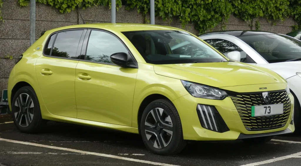 Silver Peugeot e-208 electric car parked on a sunny street.