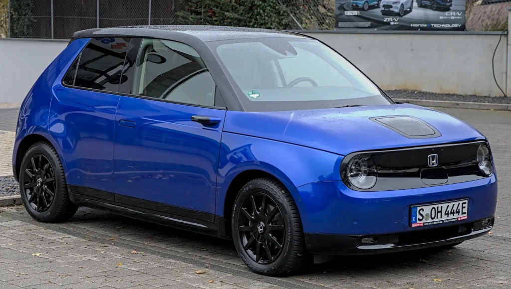 Compact electric Honda E car, parked on a city street.
