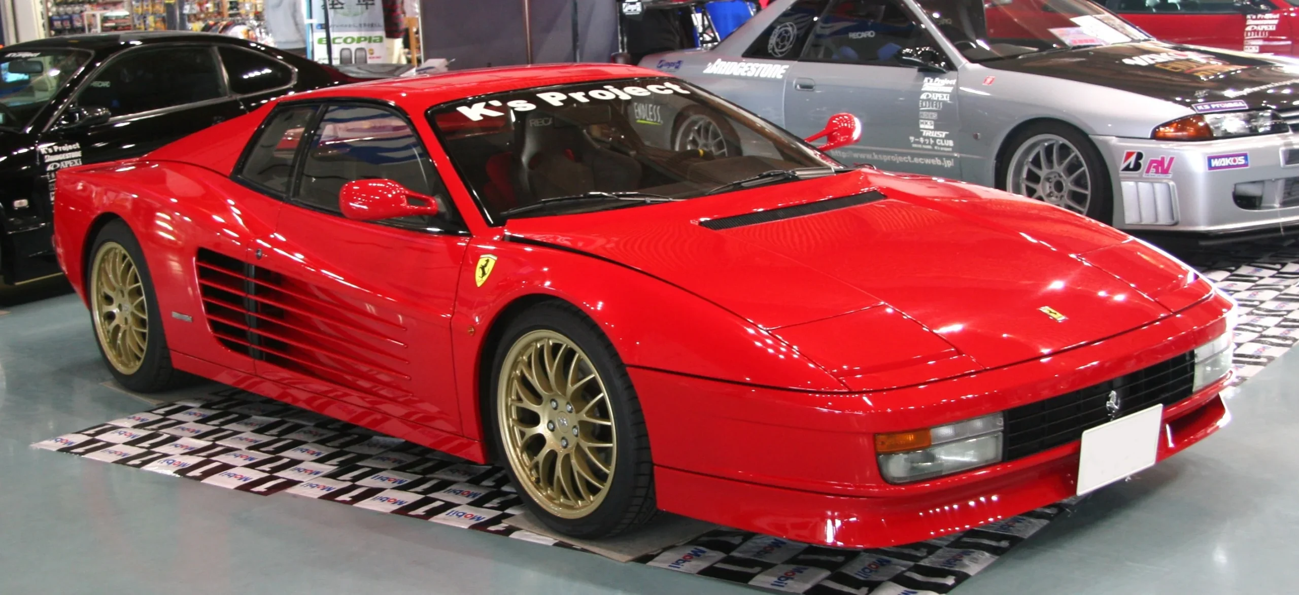 Red Ferrari Testarossa parked on a sun-drenched street, iconic 80s design.