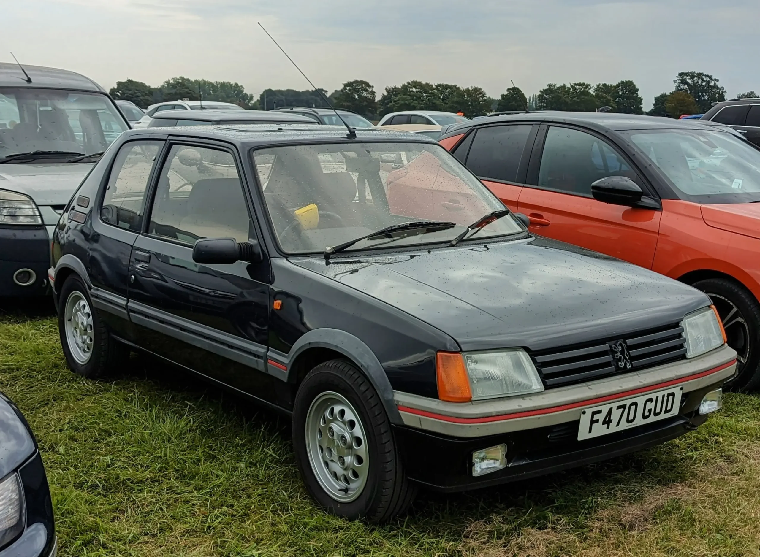 Classic Peugeot 205 GTI, a hot hatch icon, parked on street.