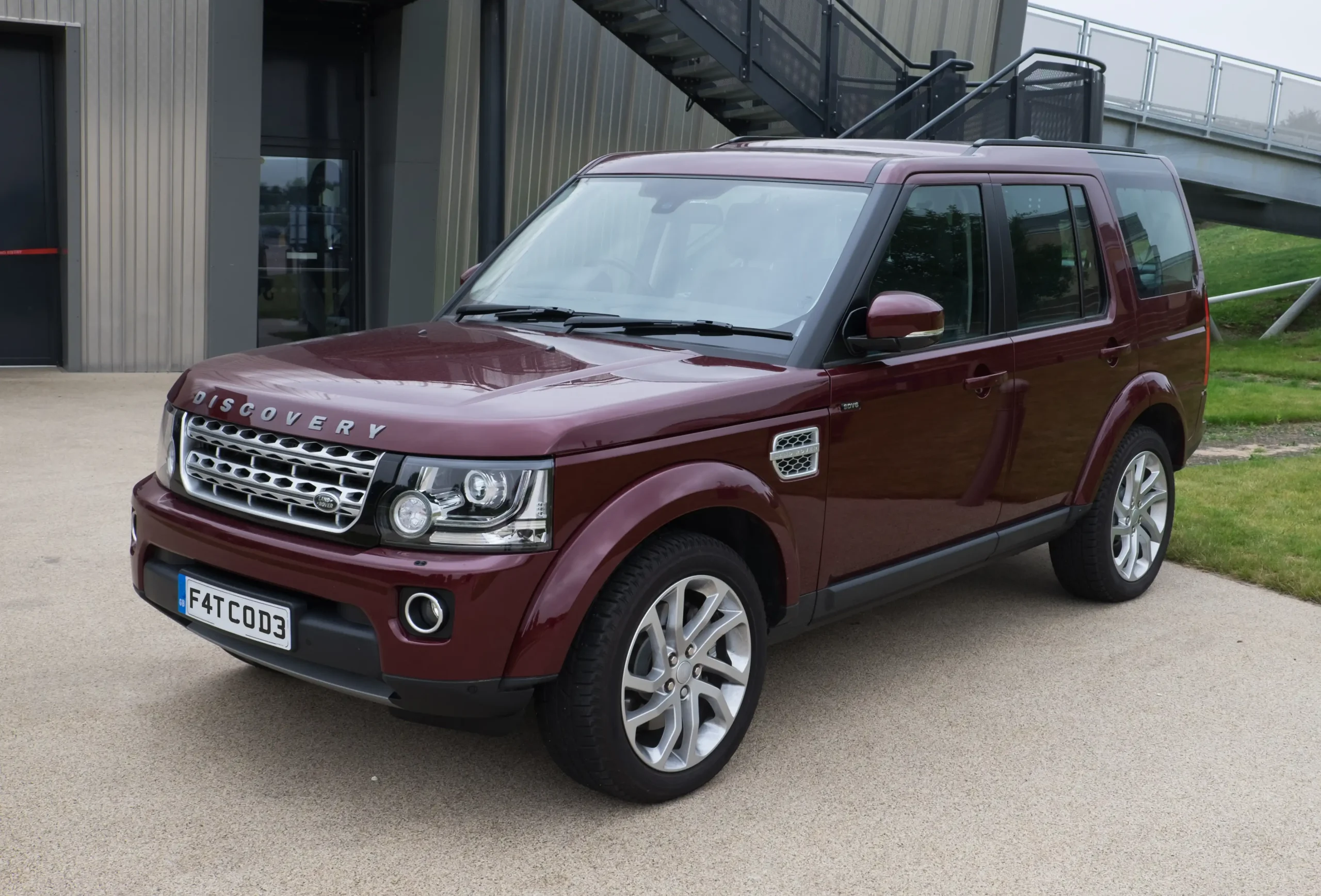 Silver Land Rover Discovery parked on a grassy hill, sunny day.