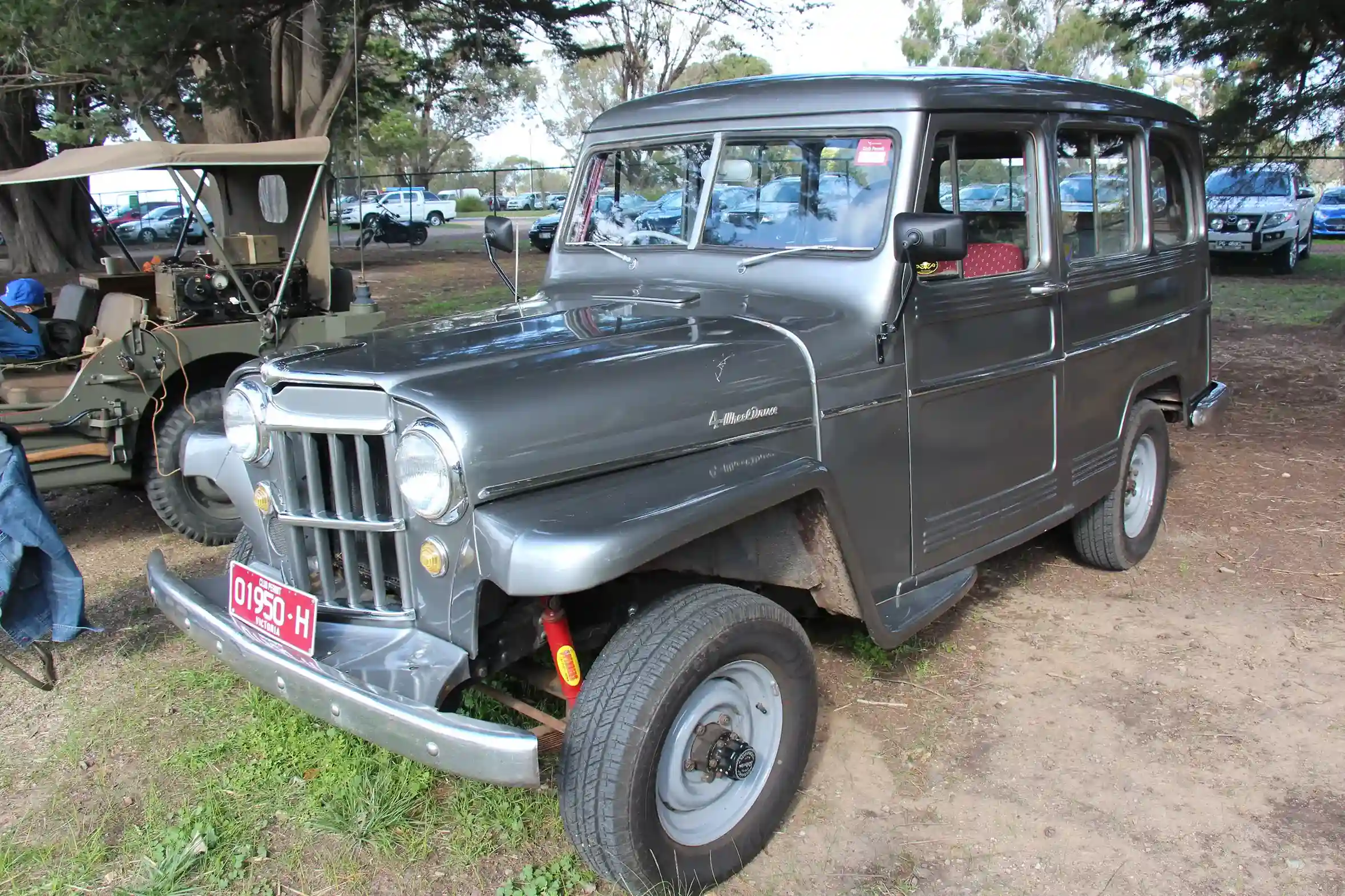 Classic two-tone 1957 Willys Jeep Station Wagon parked outside.