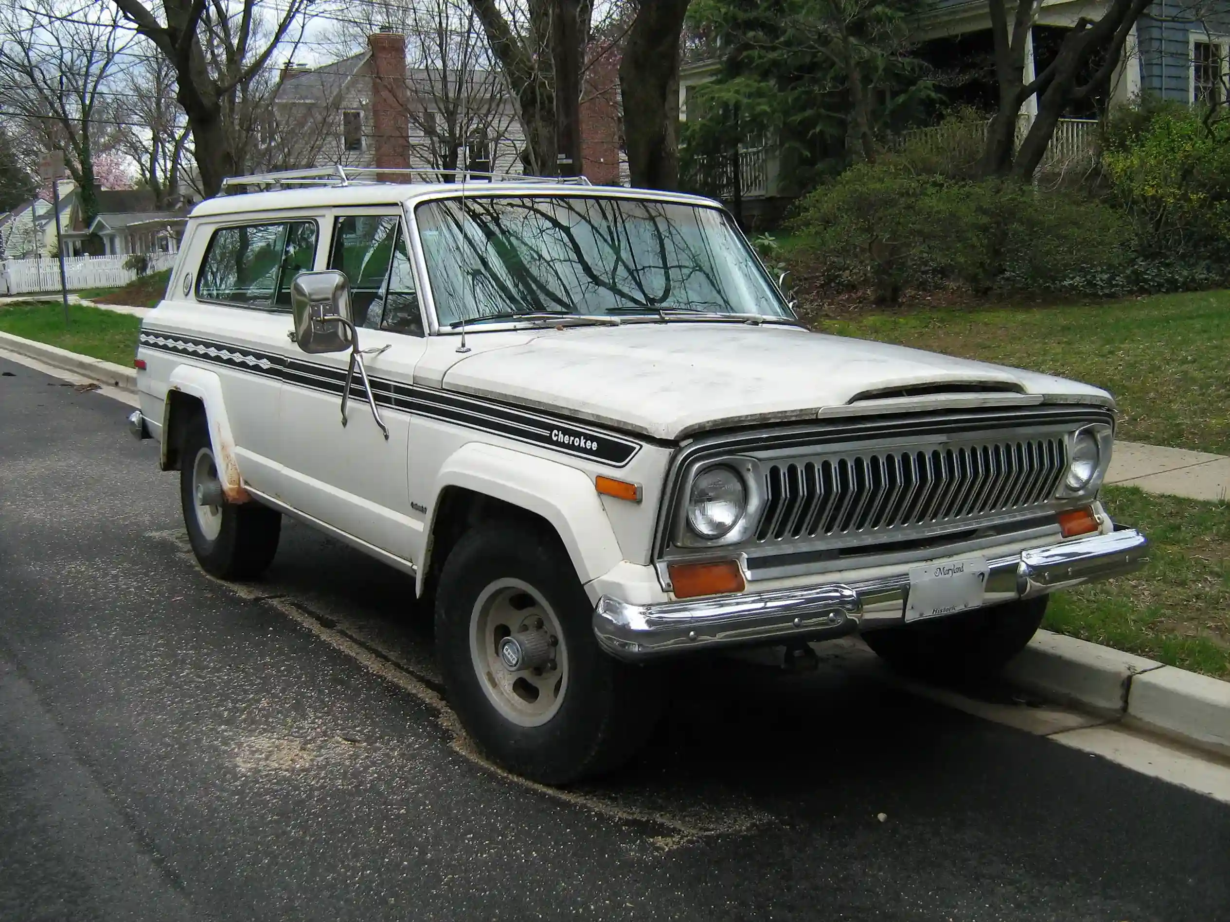 Classic Jeep Cherokee SJ parked on a sunny, winding road
