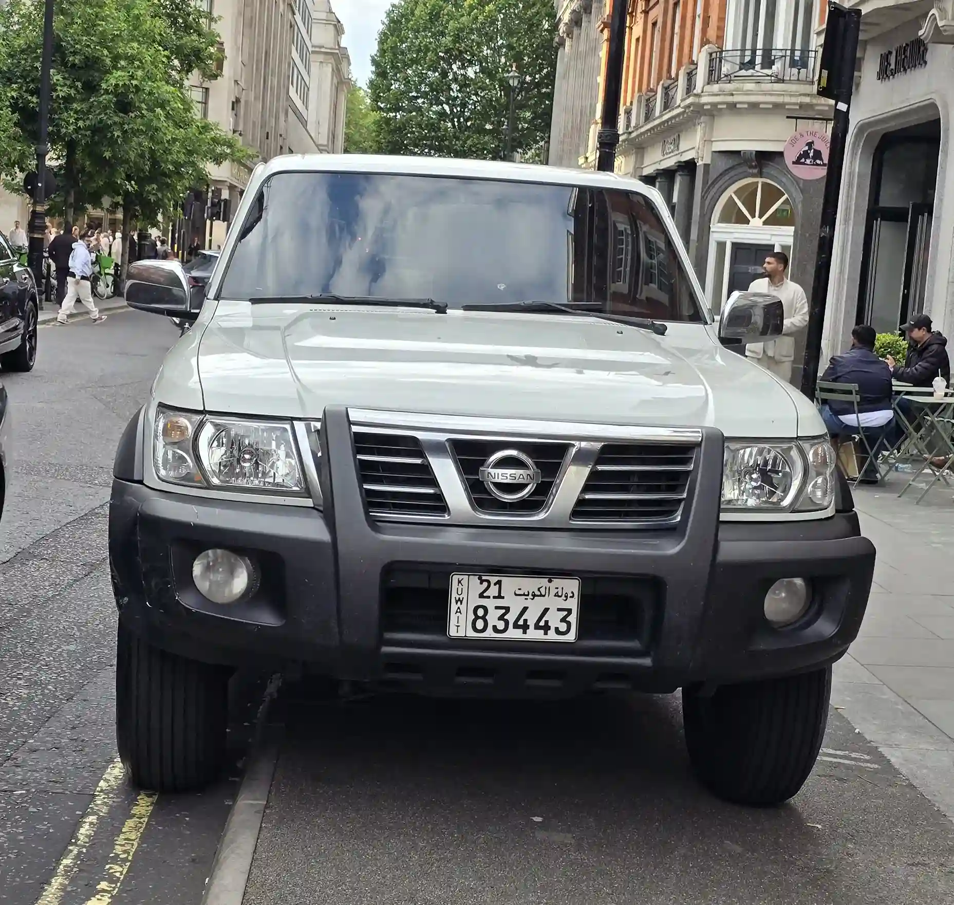 Silver Nissan Patrol SUV driving on a desert road. Rugged and powerful.