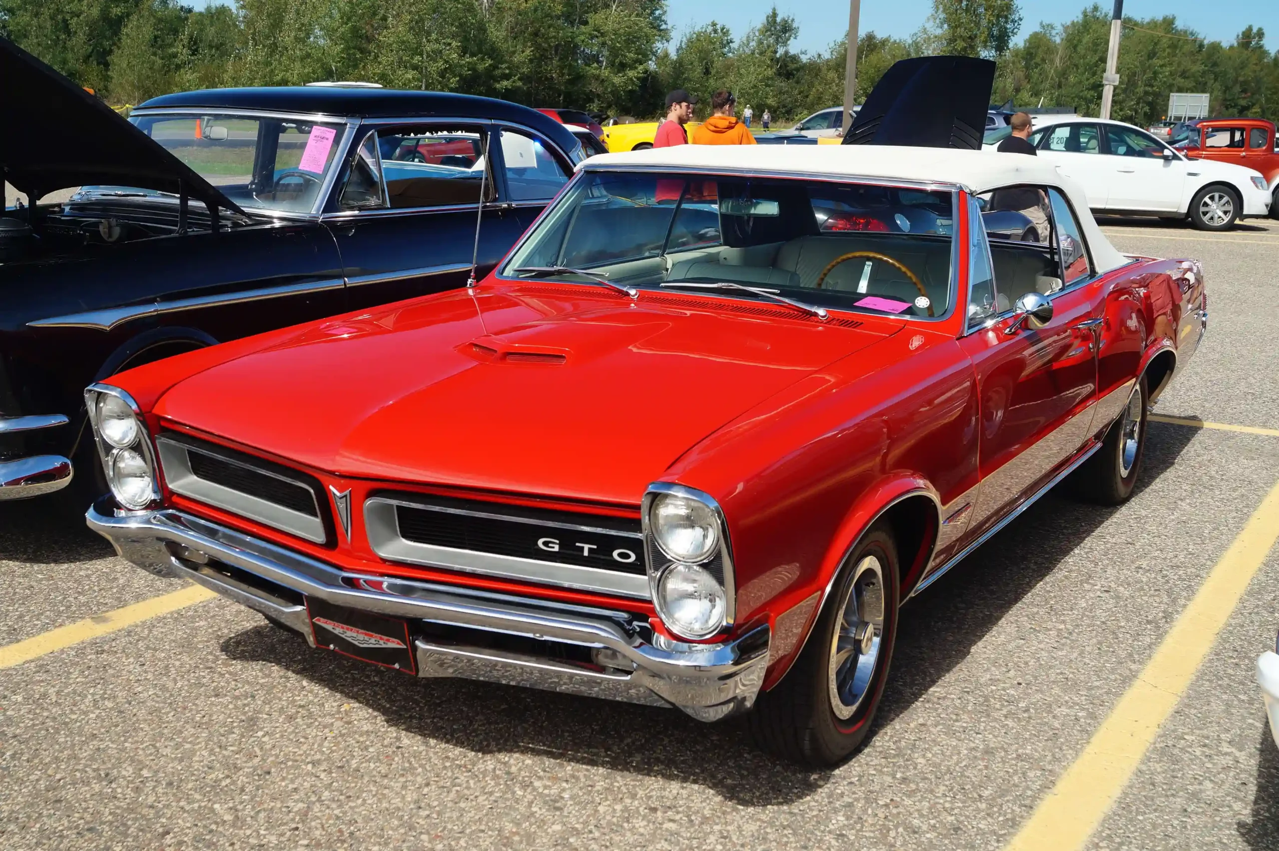 A red 1965 Pontiac GTO parked on a sunny street