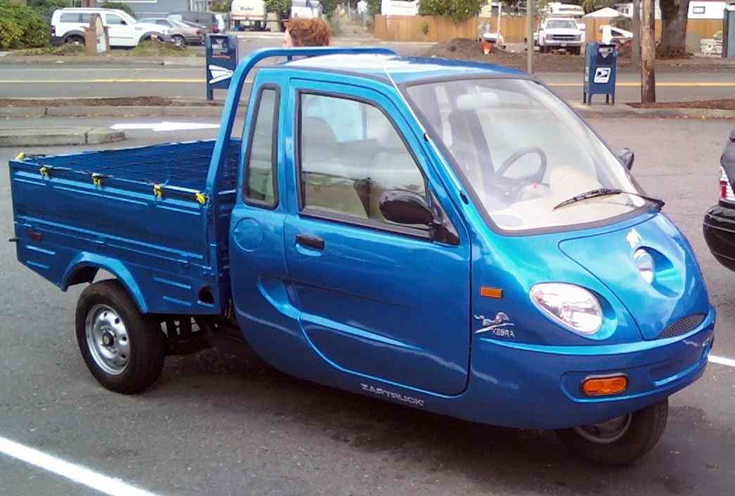 Three-wheeled ZAP Xebra electric vehicle parked on a city street.