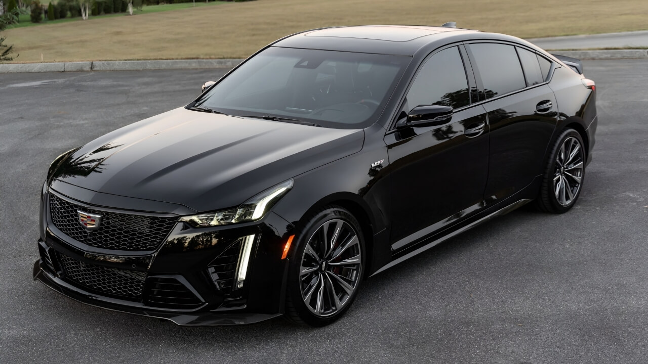 Black Cadillac CT5-V Blackwing with aggressive styling and large wheels parked on asphalt road surface