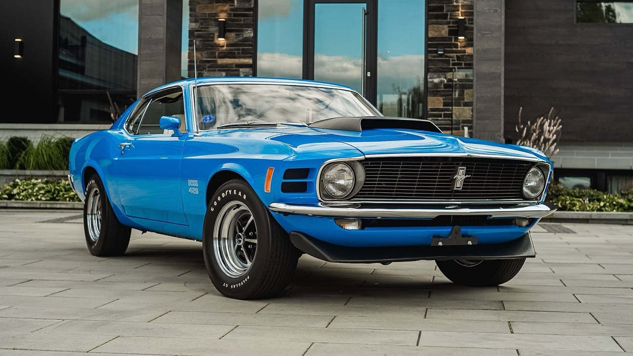Bright blue 1970 Ford Mustang Boss 429 muscle car with black racing stripes parked on modern pavement