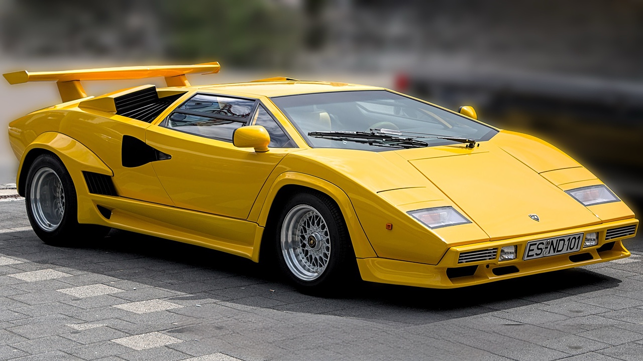 Yellow Lamborghini Countach with distinctive wedge-shaped design and large rear wing parked on asphalt surface