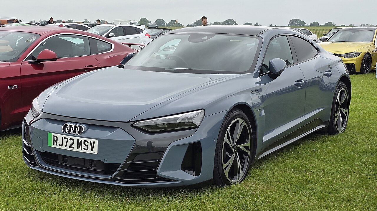 Gray Audi e-tron GT quattro electric vehicle with UK license plate parked on grass at outdoor car show event