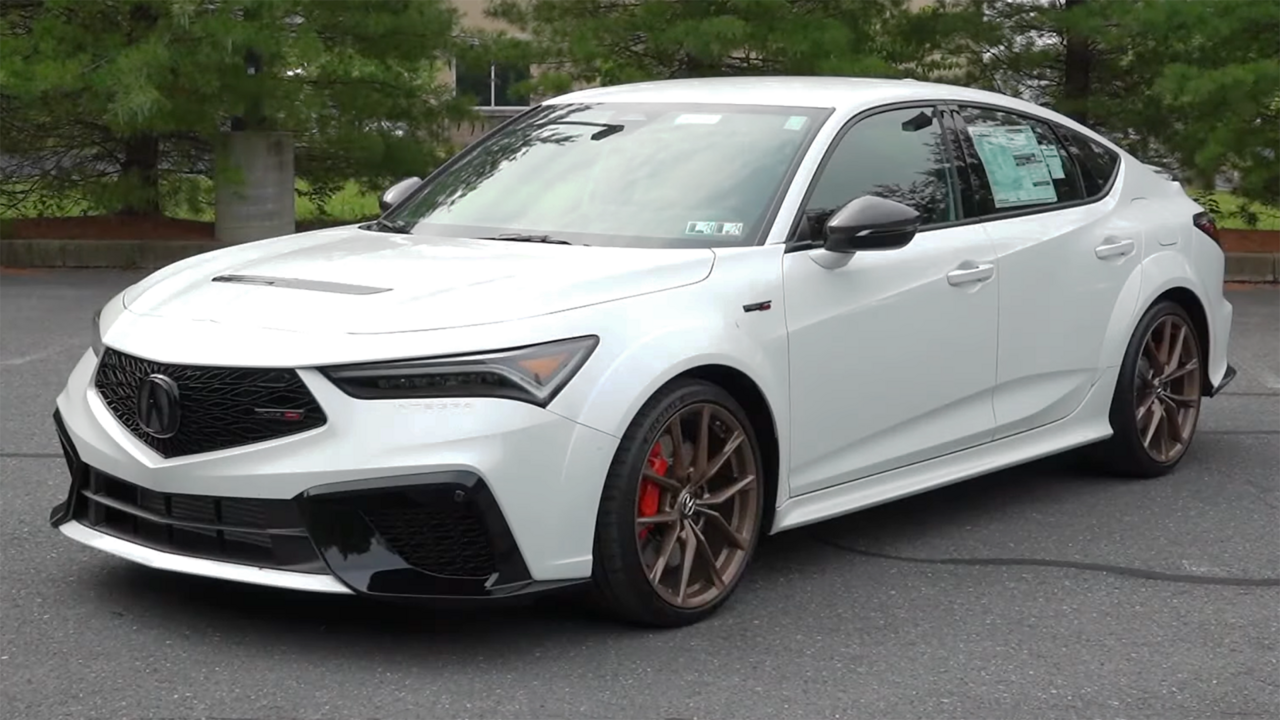 White Acura Integra Type S with red brake calipers and bronze wheels parked on asphalt with trees in background