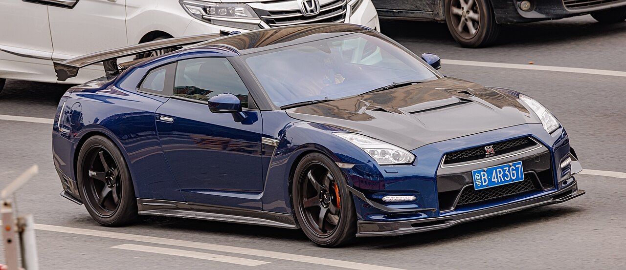 Dark blue Nissan GT-R (R35) sports car with black wheels and aerodynamic body kit parked on street