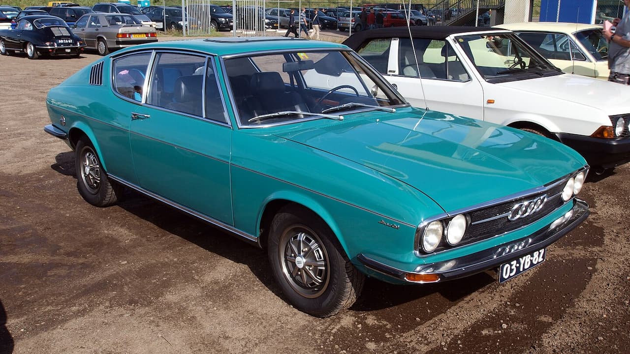 Turquoise 1973 Audi 100 Coupe S with Dutch license plate parked at car show with other vintage vehicles