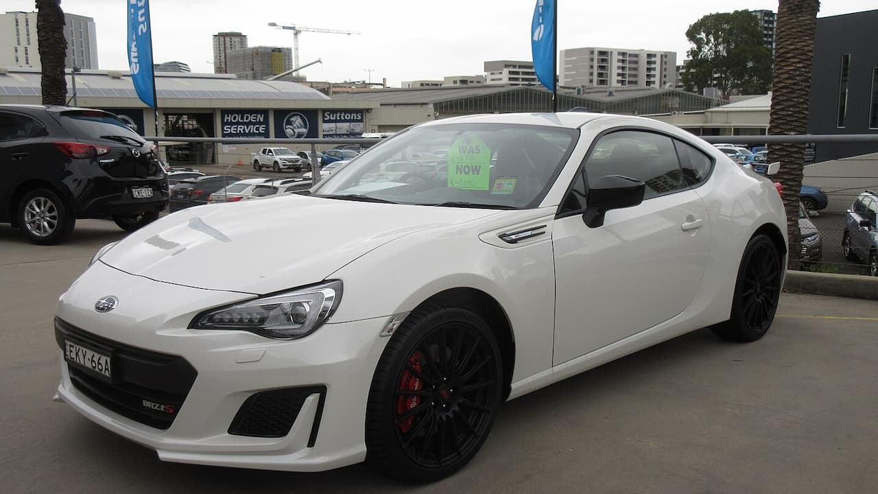 White Subaru BRZ tS with black wheels and red brake calipers parked at dealership lot