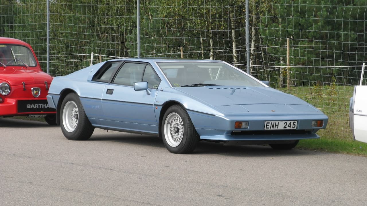 Light blue Lotus Esprit with UK license plate and wire wheels parked at car show beside other vehicles
