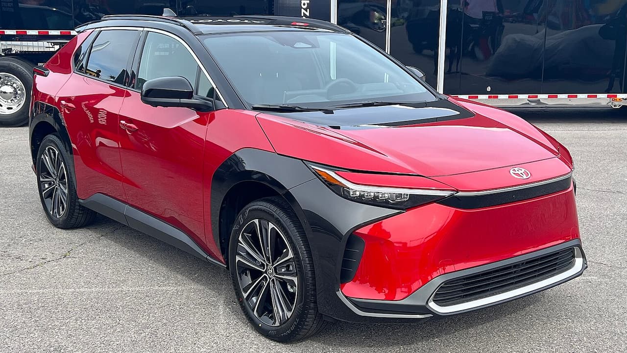 Red 2025 Toyota bZ4X electric SUV with distinctive angular headlights, black wheel arch cladding, and large alloy wheels