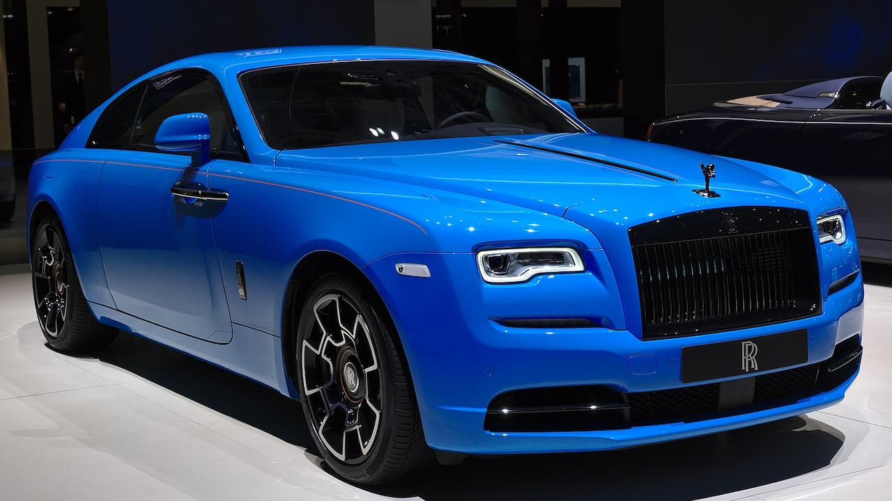 Blue Rolls-Royce Wraith displayed on white showroom floor with Spirit of Ecstasy hood ornament and black grille