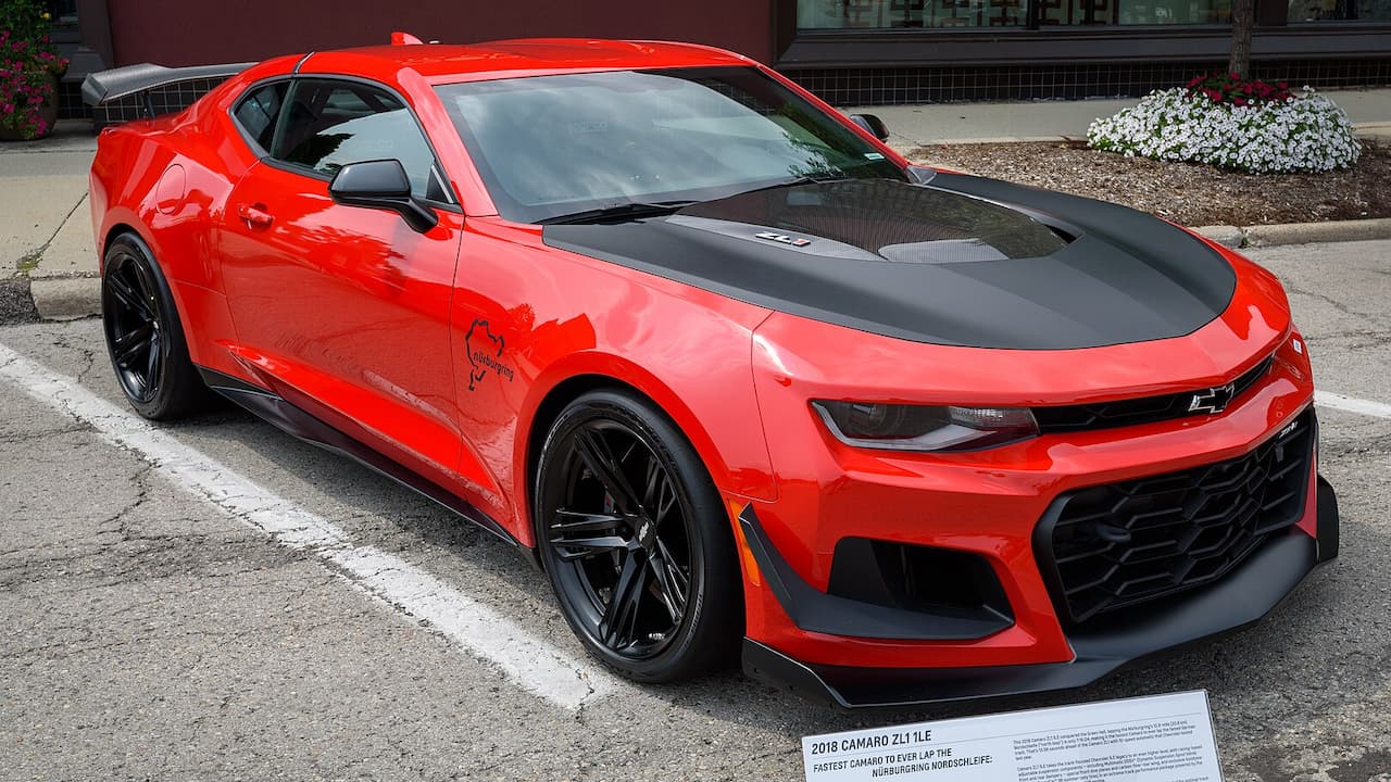 Red 2018 Chevrolet Camaro ZL1 1LE with black racing stripes and aerodynamic package parked on street with informational placard