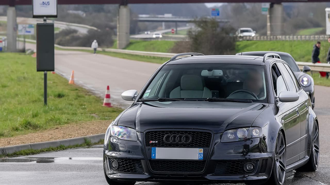 Dark gray Audi RS4 Avant (B7) parked on street with traffic cones and highway infrastructure in background