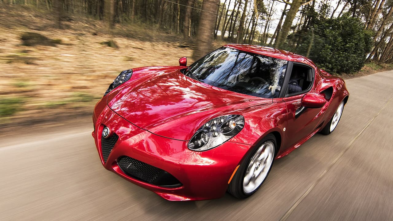 Red Alfa Romeo 4C driving on forest road with motion blur and trees in background