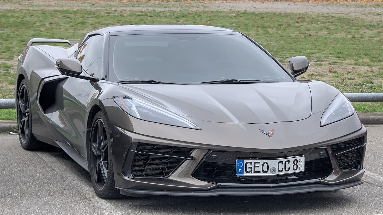 Gray Chevrolet Corvette C8 with aggressive front splitter, black wheels, and German license plate parked roadside