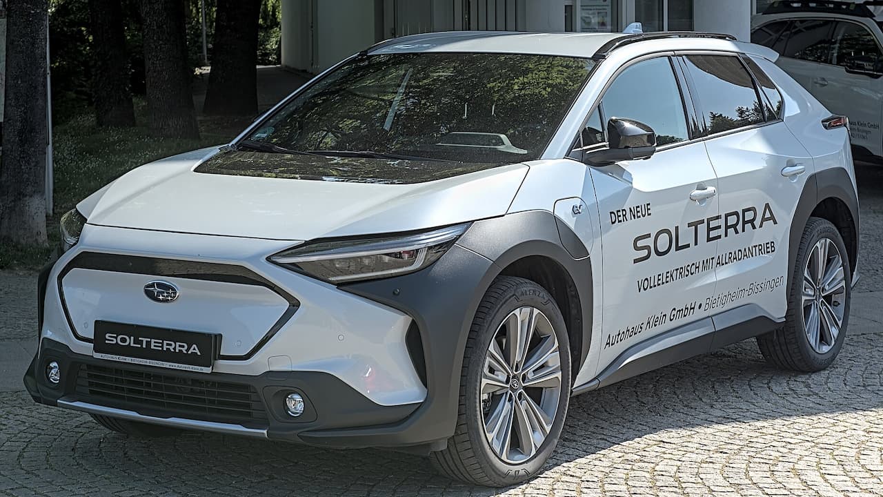 White 2025 Subaru Solterra electric SUV parked on cobblestone street with German dealership text on side panel