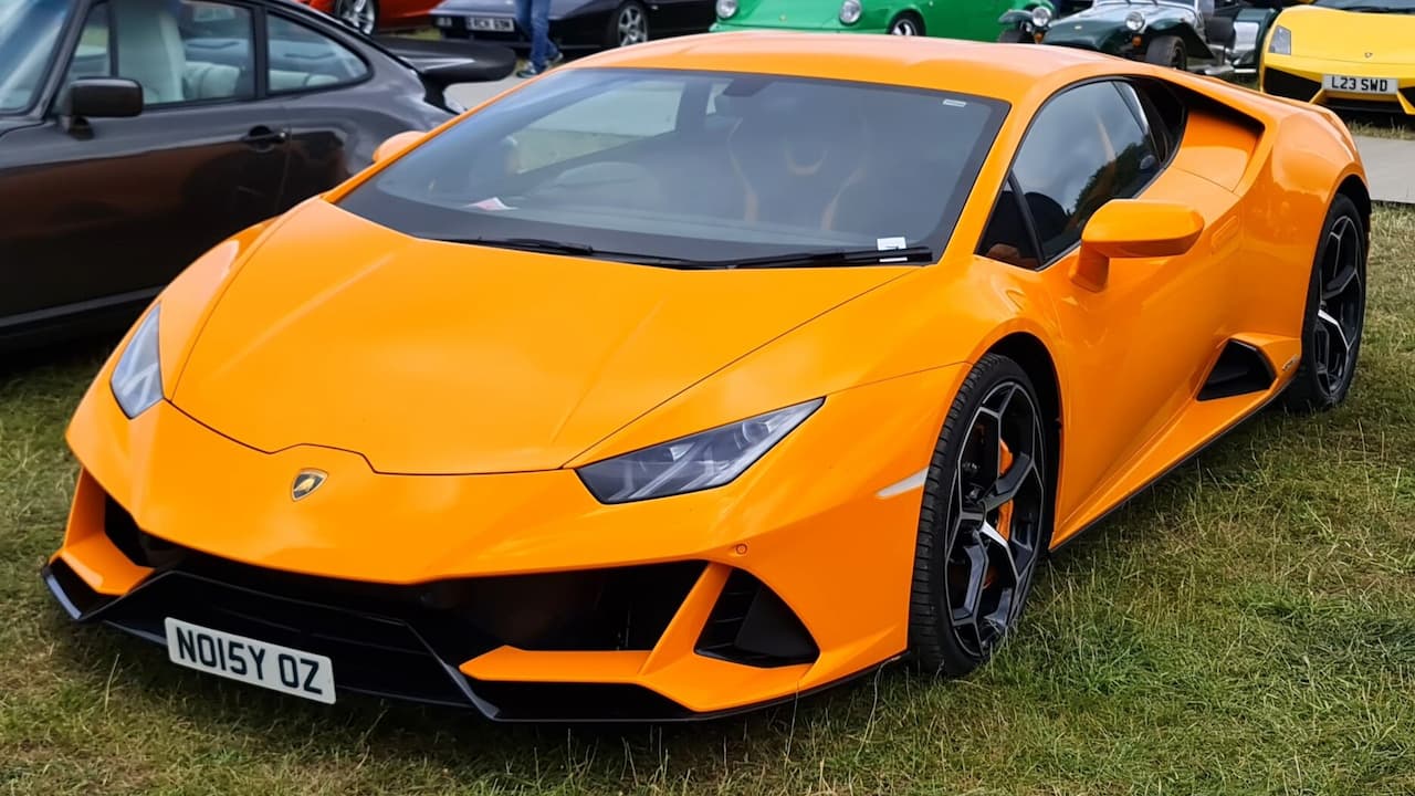 Orange Lamborghini Huracán EVO with license plate "NO15Y OZ" parked on grass at outdoor car show event