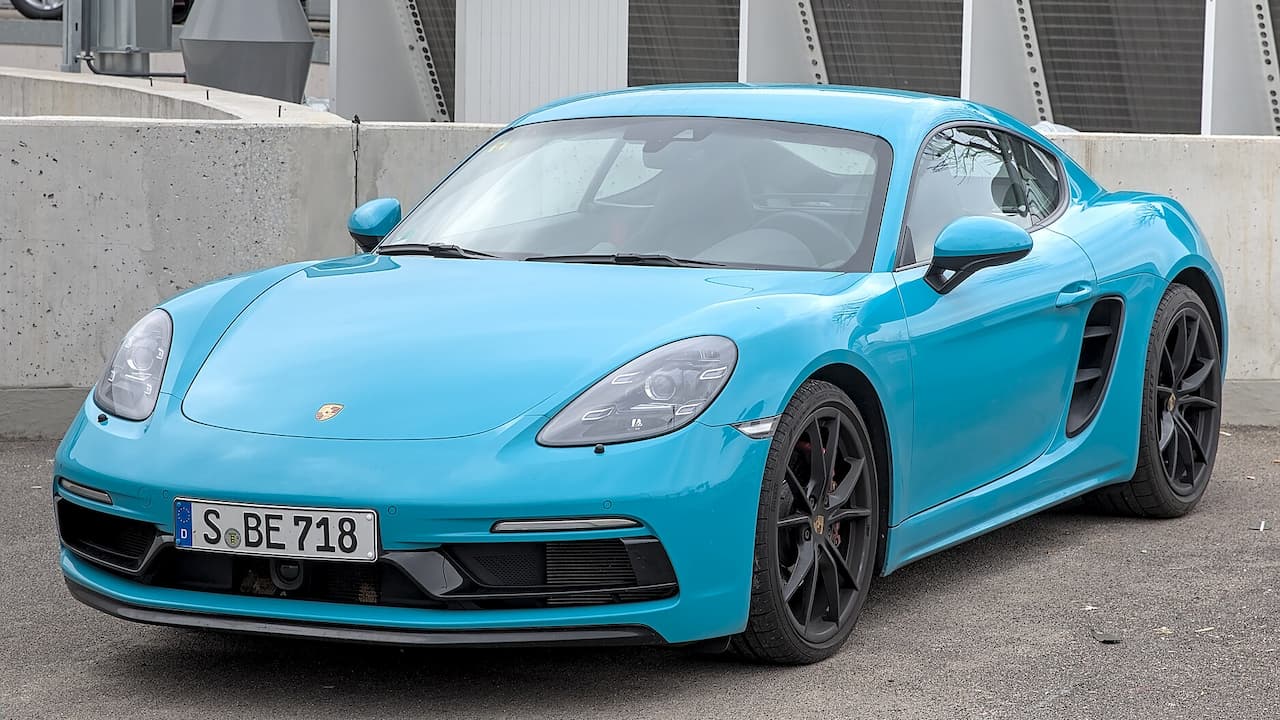 Turquoise Porsche 718 Cayman sports car parked under concrete bridge with German license plate and distinctive side air intakes