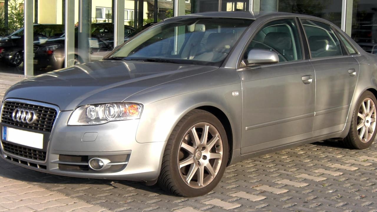 Silver Audi A4 B7 parked on cobblestone street outside car dealership with distinctive single-frame grille and alloy wheels